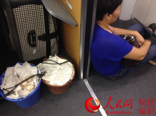 怕碰壞給孩子補充營養(yǎng)的蛋，她把兩個桶移到車廂，自己坐在過道旁的地上。林長生 攝