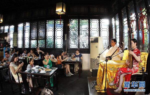7月20日早晨，游客在參加蘇州拙政園“私人定制”的早游之后邊品嘗當?shù)孛朗尺呅蕾p蘇州評彈。為避開炎夏高溫，蘇州拙政園推出“私人定制”早游活動。