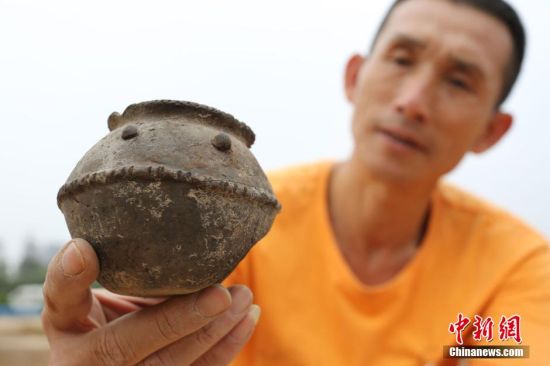 圖為考古工作人員展示出土的帶有腰帶紋的仰韶文化時期的小黑陶罐 圖為考古工作人員展示出土的帶有腰帶紋的仰韶文化時期的小黑陶罐