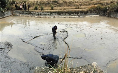 12月11日，陬市鎮青龍村連魚口組堆放工業廢料護壩的下游沉淀池內，施工人員將原本紅色的水排出，然后清淤。據涉事企業相關負責人介紹，清淤結束后，將請湖南省環境科學研究所重新規劃設計沉淀池。