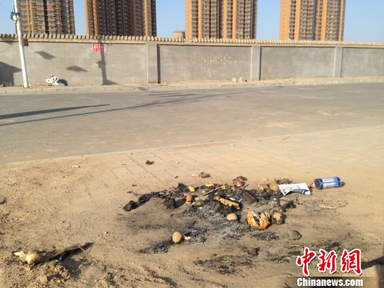 親人在何建華遇害處燃燒的紙錢和祭品。　王天譯攝