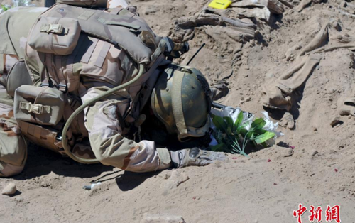 圖為一名士兵在墓地前祈禱。