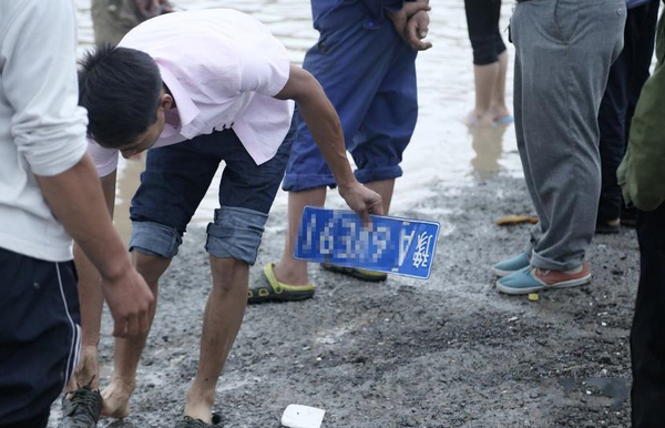 道路積水嚴(yán)重村民水中撈車牌賣錢-一個要價100元3