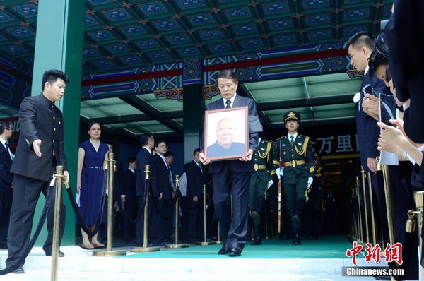 7月22日，萬里遺體在北京火化，社會各界人士前往八寶山殯儀館進(jìn)行悼念。圖為萬里兒子萬伯翱手捧遺像步出。 中新社發(fā) 盛佳鵬 攝