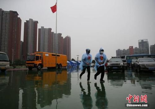 8月18日，天津泰達二小安置點內的兩名志愿者跑回樓內避雨。當日10時，天津港“8·12”特別重大火災爆炸事故所在區域下起中雨。中新社發 楊可佳 攝