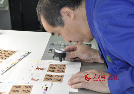 印刷車間里的工作人員正在用放大鏡檢查印刷效果。(人民網 王鶴瑾 攝)