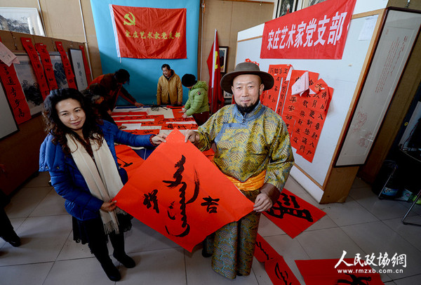北京宋莊藝術家黨支部書記巴特爾把用蒙漢兩種文字寫好的春聯送給蒙族在京的老鄉，祝愿新年吉祥。_副本