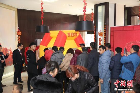 資料圖：2016年2月27日，山東東營，看房的市民在商家設置的“搶錢機”內搶著飛舞的人民幣，搶到的人民幣歸市民所有。由于房地產市場低迷，山東東營的某樓盤為了吸引前來看房的市民，在售樓處安裝了“搶錢機”，看房的市民排成長隊“搶錢”，用真金白銀刺激看房客。 圖片來源：視覺中國