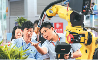 近日，在哈爾濱國際裝備制造業博覽會上，一家參展企業工作人員（右）在介紹機械臂。新華社記者 王 松攝