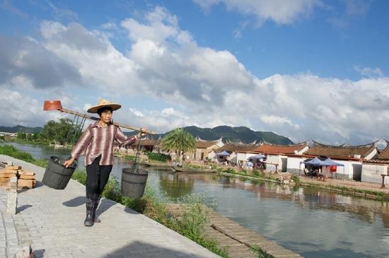 5月27日，埭美村一位村民挑桶經(jīng)過(guò)村前小河