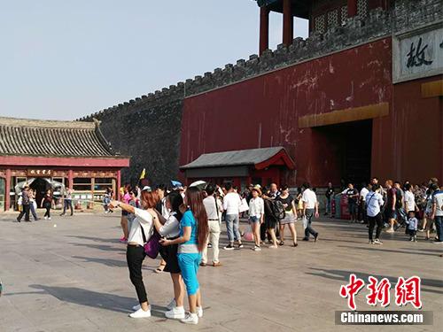 游客在故宮北門外用自拍桿合影。中新網記者 宋宇晟 攝