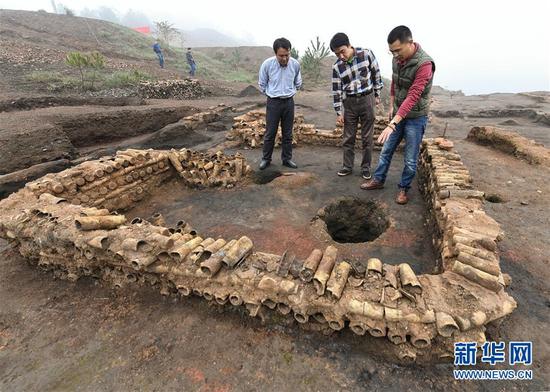 在桐木嶺礦冶遺址，考古人員查看用廢棄坩堝壘筑的房屋遺址（11月18日攝）。