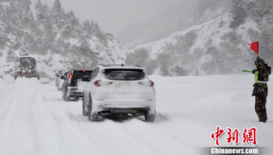 圖為武警交通第二支隊六中隊官兵在風雪現(xiàn)場安全員指揮車輛有序通行 王毅凱 攝