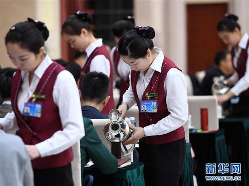 3月6日，北京華北賓館的女服務(wù)員在民盟、無黨派人士界委員聯(lián)組會上倒水。在兩會會場內(nèi)外，女代表、女委員、女工作人員、女記者在工作中盡職盡責(zé)，展現(xiàn)著自己的風(fēng)采。 新華社記者張鐸攝