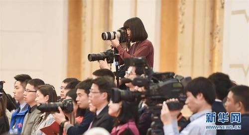 3月7日，一名女記者在十二屆全國人大五次會議江蘇代表團(tuán)全體會議上采訪拍攝。在兩會會場內(nèi)外，女代表、女委員、女工作人員、女記者在工作中盡職盡責(zé)，展現(xiàn)著自己的風(fēng)采。 新華社記者陳曄華攝