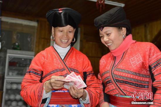 1月27日，廣西龍勝各族自治縣龍脊鎮(zhèn)大寨村的瑤嫂正在清點(diǎn)分到的梯田維護(hù)費(fèi)。1月27日至1月28日，廣西龍勝各族自治縣龍脊鎮(zhèn)大寨村村委會(huì)將110多萬(wàn)元的“紅利”分發(fā)到200多戶的群眾手中。龍脊鎮(zhèn)大寨村從2003年開寨接待游客以來(lái)，該縣通過(guò)旅游扶貧方式引導(dǎo)該村群眾以梯田入股方式與當(dāng)?shù)氐凝埣孤糜喂韭?lián)營(yíng)，旅游公司則將門票收入按一定的比例為當(dāng)?shù)氐拇迕癜l(fā)放梯田維護(hù)費(fèi)。目前，大寨村的游客多了，大部分村民開設(shè)了農(nóng)家旅館，和販賣瑤族工藝品等，使其成為當(dāng)?shù)厝罕娫鍪罩赂坏闹饕馈?lt;a target='_blank' href='http://www.chinanews.com/'>中新社</a>發(fā) 韋吉陽(yáng) 攝