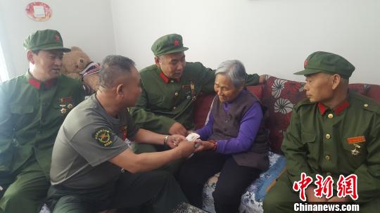 圖為老兵們將慰問金送到門二柱母親手中。　呂新穎 攝