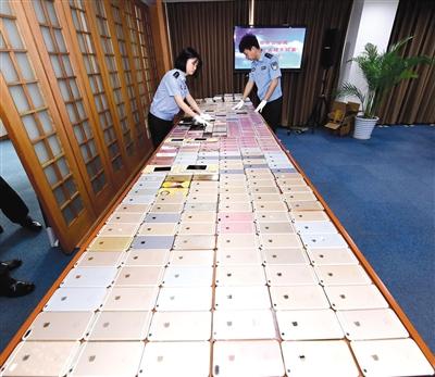 北京警方破獲特大盜銷手機團伙，起獲的525部被盜手機鋪滿了一張大桌子，其中大多是蘋果手機。	警方供圖