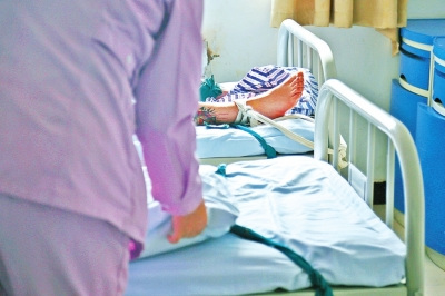 一位病人沉沉睡去，護士還在為另一位病人整理床鋪。
