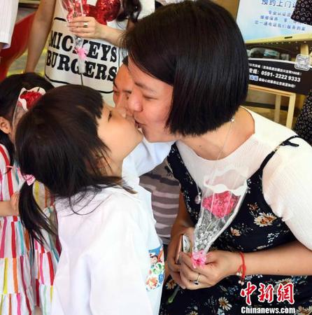 參加此次公益活動(dòng)的福州一名女童為母親送上康乃馨花束后，再獻(xiàn)深情的一吻，表愛(ài)意?！∮浾邉⒖筛?攝