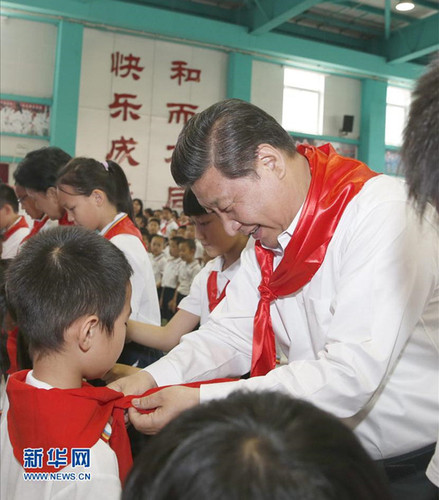 2014年5月30日，在北京市海淀區(qū)民族小學(xué)的少先隊(duì)入隊(duì)儀式上，習(xí)近平為新少先隊(duì)員系上紅領(lǐng)巾。新華社記者鞠鵬攝