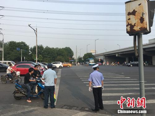 6月21日上午，北京仰山橋下十字路口，執勤人員要求非機動車停在停止線后。湯琪 攝