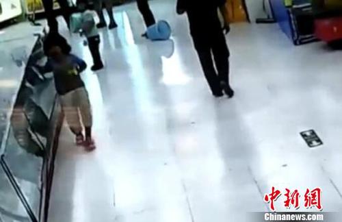 被市民拉開后，女童扶著柜臺一瘸一倒的離去。(視頻截圖)