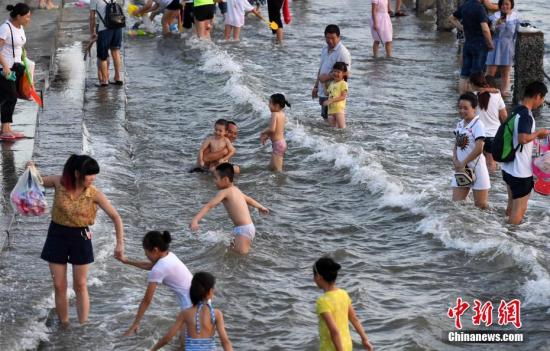 7月4日傍晚，市民們帶著小孩在海邊戲水消暑。連日來，受副熱帶高壓影響廈門地區持續高溫。 張斌 攝