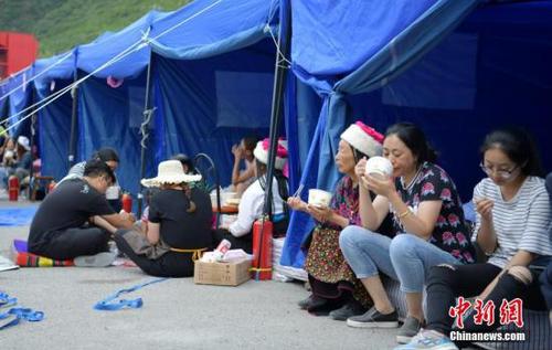 8月10日，四川九寨溝“8.8”地震震源中心附近的臨時安置點，受災村民在帳篷邊吃飯。<a target='_blank' href='http://www.chinanews.com/'>中新社</a>記者 劉忠俊 攝