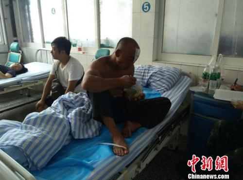 獲救漁民丁兆蘭光著上身，左額頭用紗布包著，正在吃著醫務人員送來的午飯。于從文 攝