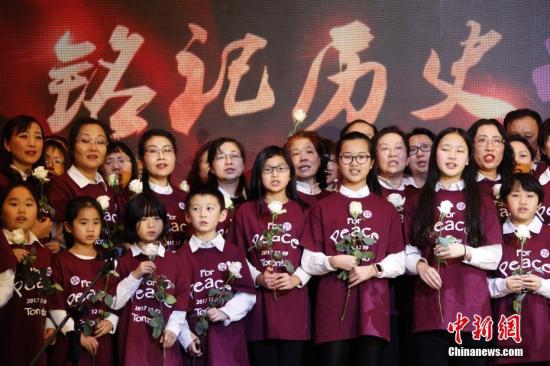 當地時間12月9日，加拿大安大略省各界華人共同舉辦的“南京大屠殺80周年追思會”在多倫多舉行。來自華人社區及其他多個族裔社區的逾千名代表參加此次主題為“銘記歷史，祈愿和平”的追思會。圖為社區人士與孩子們在追思會上合唱《讓世界充滿愛》。 <a target='_blank' href='http://www.chinanews.com/'>中新社</a>記者 余瑞冬 攝