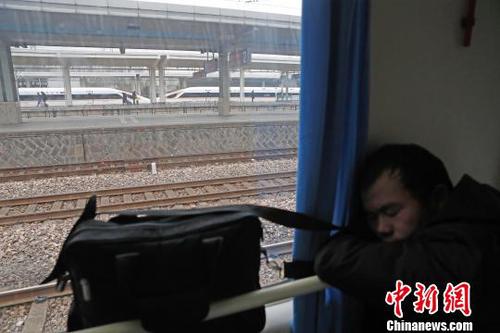 一路上旅客們趴在扶手上睡覺，顧不上身邊經(jīng)過的復(fù)興號列車。　殷立勤 攝
