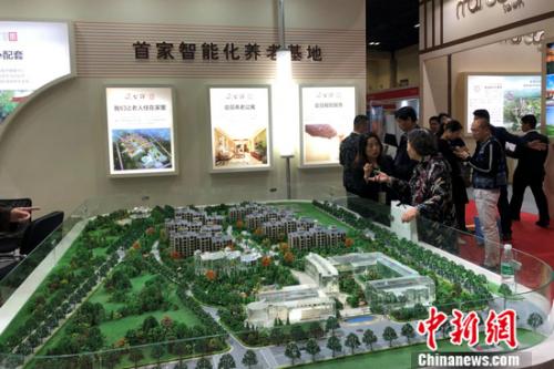 2018北京春季房展會上某養老地產項目的工作人員在向觀眾進行介紹。程春雨 攝