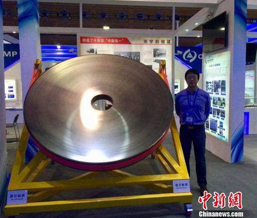 張舸博士和展出的碳化硅反射鏡。中科院長(zhǎng)春光機(jī)所供圖