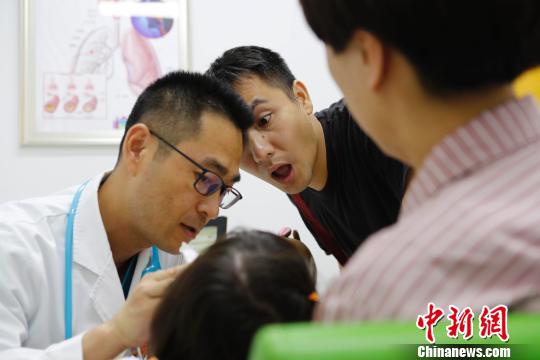 門診醫(yī)生正在耐心的給家長講解孩子的病情。　殷立勤　攝