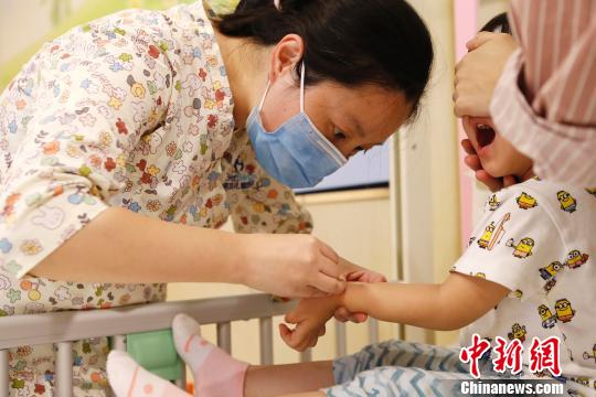 醫(yī)護(hù)人員正在為孩子進(jìn)行輸液前的準(zhǔn)備工作。　殷立勤　攝