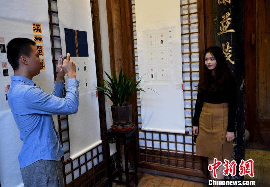 一名“90后”女大學生篆刻作者在自己創作的作品前留影?！∮浾邉⒖筛?攝