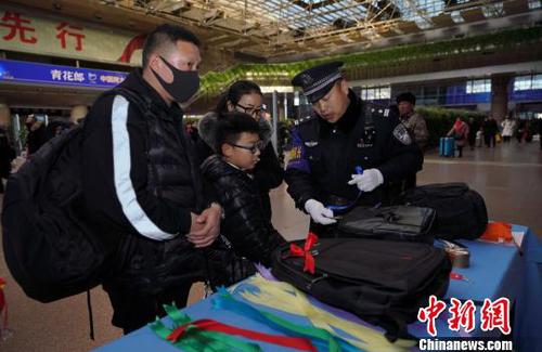 12月28日，北京西站派出所民警為背黑色雙肩包的旅客系上個性小標(biāo)識，以防在通過安檢或乘車過程中出現(xiàn)錯拿情況。(完) 龐賀雷 攝