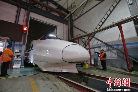 一列動車組駛入車庫，機械師位列兩邊檢查車體外觀?！《〔?攝