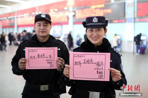 2月1日，隨著春節(jié)臨近，南京鐵路公安處南京站派出所的民警在紙上寫下“平安春運(yùn)，有我們護(hù)航”、“天下無賊是我們最大的心愿”、“平安歸途么么噠”等話語，用別樣的方式給旅客們送上溫馨的新年祝福。圖為南京火車站售票大廳內(nèi)的值班民警和特勤送出溫馨祝福語。中新社記者 泱波 攝