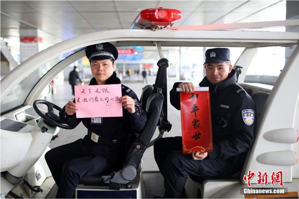 2月1日，隨著春節(jié)臨近，南京鐵路公安處南京站派出所的民警在紙上寫下“平安春運(yùn)，有我們護(hù)航”、“天下無賊是我們最大的心愿”、“平安歸途么么噠”等話語，用別樣的方式給旅客們送上溫馨的新年祝福。圖為南京火車站周邊巡邏民警和特勤送出溫馨祝福語。中新社記者 泱波 攝