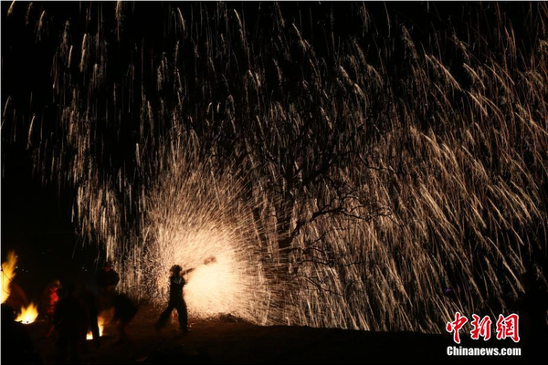 該村“打樹花”的習(xí)俗已延續(xù)了近600年，村民將生鐵融成鐵水后，再用特制的木板將鐵水擊打至樹上，頓時綻放出萬點(diǎn)“鐵花”。中新社記者 陳昊 攝