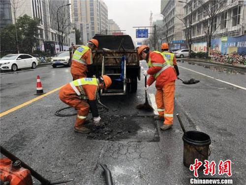 環衛工人修補雨天侵蝕的瀝青路面。　西湖區城管局提供 攝