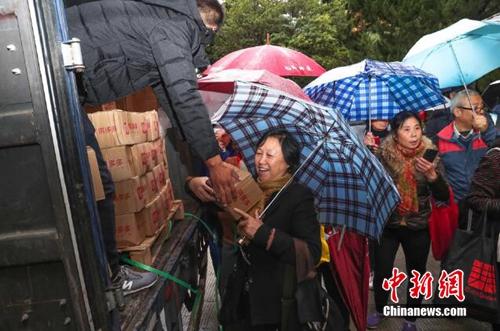 資料圖：上海百名居民在雨中排成一條長龍，領取剛到貨的秭歸臍橙。供圖