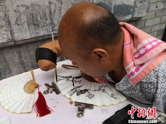 賈維軍在扇面上寫字?！“⒘漳?攝