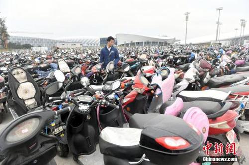 12月14日，福州倉山南二環(huán)附近的臨時停車場停放超過2.2萬輛無牌、超標(biāo)電動車，場面震撼。福州市交警一個多月來共查處電動車各類交通違法14萬多起，暫扣無牌、超標(biāo)電動車2.2萬多輛。圖為市民憑有效證件及購車發(fā)票領(lǐng)回被扣車輛。<a target='_blank' href='http://www.chinanews.com/'>中新社</a>記者 呂明 攝