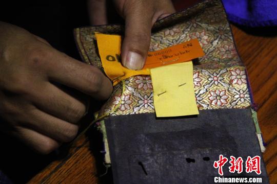 圖為羅布林卡管理處工作人員將編號縫在古籍外側(cè)。　趙朗 攝