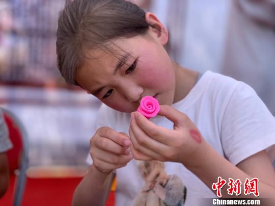 圖為小女孩正在用米塑捏玫瑰花。　孫睿 攝