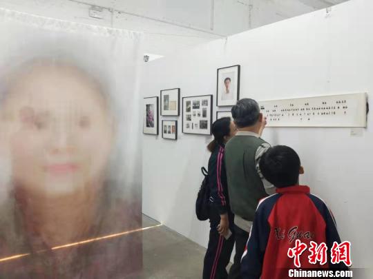 在第19屆中國平遙國際攝影大展柴油機展區的一角，一張大幅的人像彩畫吸引來往游客駐足拍照。　楊佩佩 攝
