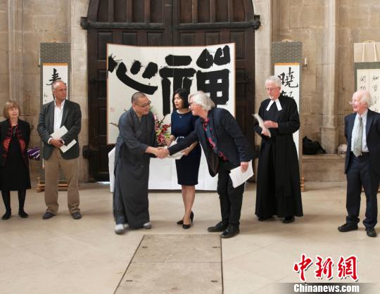 英國皇家水彩協(xié)會前主席大衛(wèi)·帕斯特(右3)與月真法師(左3)握手，恭賀展覽開幕 。??　王子嵐 攝